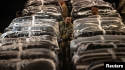 FILE —U.S. service members secure humanitarian aid, bound for airdrop over Gaza, onto a cargo aircraft at an undisclosed location within the U.S. Central Command area of responsibility, March 1, 2024.