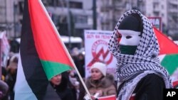 FILE - A masked protester raises a Palestinian flag during a rally in support of Palestinians, in Athens, Greece, January 13, 2024.