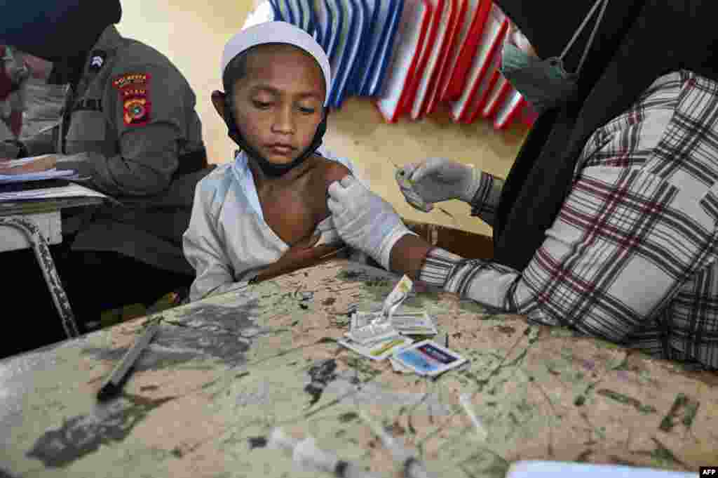 Seorang siswa SD menerima vaksin COVID-19 &quot;Sinovac&quot; di sebuah sekolah dasar &quot;Darul Imarah&quot;, provinsi Aceh. (Foto: Chaideer Mahyuddin / AFP)