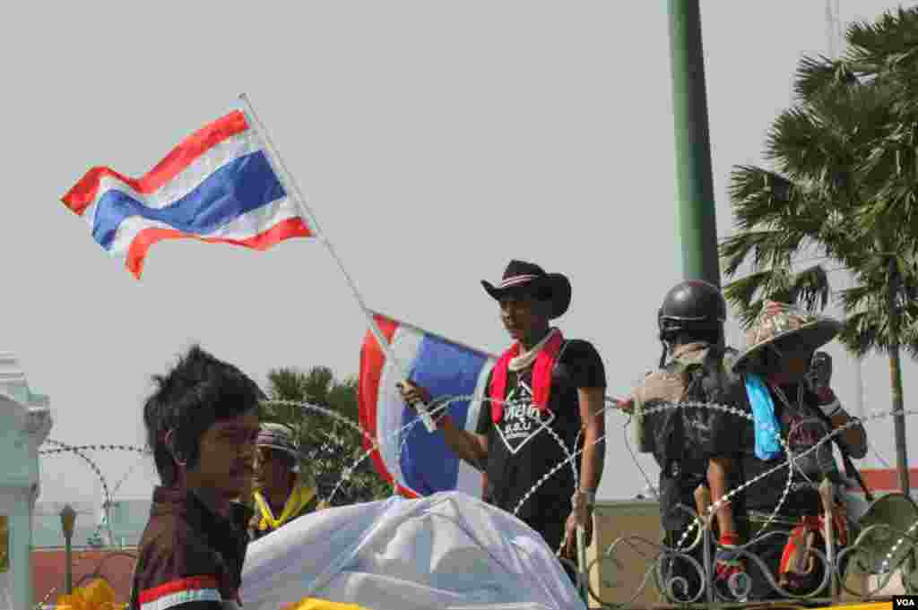 A protester waves a Thai flag at the entrance of Government House after barricades were taken down, Bangkok, Dec. 3, 2013. (Steve Herman/VOA)