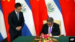 El ministro de Relaciones Exteriores de El Salvador, Carlos Castañeda, (derecha) firma documentos en una ceremonia para el establecimiento de relaciones diplomáticas de El Salvador con China, en Beijing, el martes, 21 de agosto de 2018.