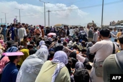Afghan people gather along a road as they wait to board a U S military aircraft to leave the country, at a military airport in Kabul, Aug. 20, 2021 days after Taliban's military takeover of Afghanistan.