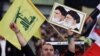 Seorang pendukung Hezbollah memegang foto tokoh revolusioner Iran Ayatollah Khomeini (kiri) dan pemimpin tertinggi di Iran Ayatollah Ali Khamenei (kanan) dalam aksi unjuk rasa yang dipimpin oleh Hezbollah di Beirut, Lebanon, pada 17 April 2015. (Foto: AP/Bilal Hussein)