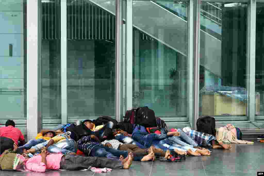 Migrant laborers rest outside the departure lounge of the Netaji Subhash Chandra Bose International Airport as their flights are cancelled during a day long state-imposed lockdown in Kolkata, India.