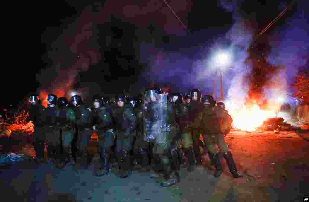 Ukrainian riot police prepare to push back demonstrators, who planned to stop buses carrying passengers evacuated from the Chinese city of Wuhan, outside Novi Sarzhany, to protest against their arrival.