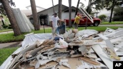 Jose Martinez, left, and William Majano remove drywall and baseboards from a home damaged by floodwaters from Tropical Storm Harvey, Aug. 30, 2017, in Houston.