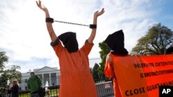 FILE - People protest at the White House in Washington against continuing detentions at the Guantanamo Bay center and Bagram prison, Oct. 24, 2014.
