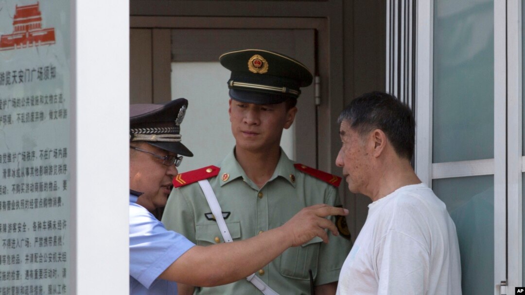 Polisi berbicara pada seorang warga yang ditahan di pos pemeriksaan di Lapangan Tiananmen di Beijing (4/6). (AP/Ng Han Guan)