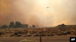 Dalam foto iyang dikirim oleh Vince O'Daye ini, nampak sebuah helikopter terbang di atas gumpalan asap dari api di kawasan yang dihuni oleh masyarakat Sutcliffe, Nevada, sekitar 56,4 kilometer sebelah utara Reno, Nevada, 30 Juli 2016. (Foto: dok).