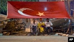 Protesters man a barricade near Gezi park, in Istanbul June 15, 2013, while others in Gezi Park debate the prime minister's proposal to end their park occupation.