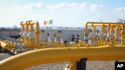 FILE - Men stand next to pipelines of the national natural gas distribution network outside Ungheni, Moldova, March 4, 2015.