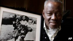 Le photographe sud-africain Sam Nzima pose avec sa photo emblématique montrant Hector Pieterson, 13 ans, porté après avoir été abattu par la police de l'apartheid lors du soulèvement de Soweto en 1976, à Pretoria, le 27 avril 2011.
