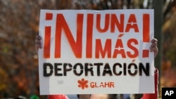 FILE - A man marches with a sign during a protest in front of a building that houses federal immigration offices.