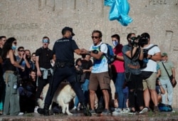 A police officer confronts a protester at a rally against the use of protective masks amid the coronavirus pandemic, in Madrid, Spain, Aug. 16, 2020.