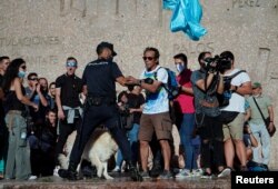 A police officer confronts a protester at a rally against the use of protective masks amid the coronavirus pandemic, in Madrid, Spain, Aug. 16, 2020.