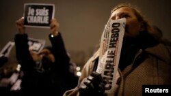 A man holds a copy of weekly satirical magazine Charlie Hebdo to pay tribute during a gathering at the Place de la Republique in Paris Jan. 7, 2015. Seorang pria memegang sebuah eksemplar tabloid Charlie Hebdo