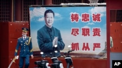 FILE - A Chinese honor guard member walks past a poster of Chinese leader Xi Jinping near the entrance to the Forbidden City in Beijing, Sept. 18, 2021. 