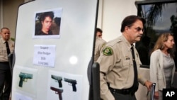 FILE - In this May 24, 2014 file photo, Santa Barbara County Sheriff Bill Brown, right, walks past a board displaying photos of gunman Elliot Rodger and the weapons he used in a mass shooting in Isla Vista, Calif.