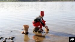 In this photo taken on Jan. 7, 2011, clad in traditional dress a woman from Kachin race uses a bamboo container to fetch water from the Irrawaddy River in Kachin State, northern Myanmar. The country's President Thein Sein called Friday, Sept. 30, 2011 for