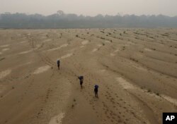 Residents transport drinking water from Humaita to the Paraizinho community, along the dry Madeira River, a tributary of the Amazon River, during the dry season, Amazonas state, Brazil, Sept. 8, 2024.