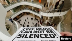 FILE - A Zaman journalist holds a banner at the headquarters of Zaman daily newspaper in Istanbul, Dec. 14, 2014. 