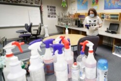 FILE - Charo Woodcock cleans a classroom at McClelland Elementary School, in Indianapolis, June 22, 2020.