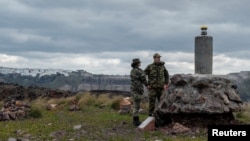 FILE - Members of Greece's military geographical team conduct geological measurements, to evaluate potential structural changes due to the ongoing seismic activity on the volcanic island of Nea Kameni, Greece, Feb. 10, 2025.