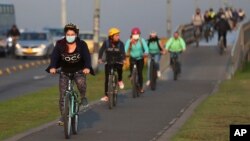 Commuters, wearing protective masks, ride their bicycles in Bogota, Colombia, Tuesday, March 17, 2020. 