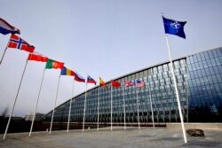 FILE - Flags of NATO alliance members flap in the wind outside NATO headquarters in Brussels, Feb. 28, 2020.