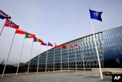 FILE - Flags of NATO alliance members flap in the wind outside NATO headquarters in Brussels, Feb. 28, 2020.