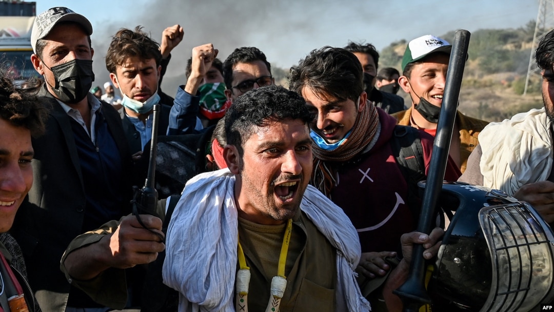 FILE - Supporters of jailed former Prime Minister Imran Khan's Pakistan Tehreek-e-Insaf party shout slogans while holding gear snatched from police during their march toward Islamabad demanding Khan's release, in Hasan Abdal, Nov. 25, 2024.