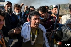 Supporters of jailed former Prime Minister Imran Khan's Pakistan Tehreek-e-Insaf party shout slogans and hold gear snatched from police during their march toward Islamabad demanding Khan's release, in Hasan Abdal, Punjab province, on Nov. 25, 2024.