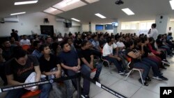 FILE - Salvadoran deportees arriving from McAllen, Texas, listen to instructions from an immigration officer at La Chacra Immigration Center in San Salvador, El Salvador, June 28, 2018.