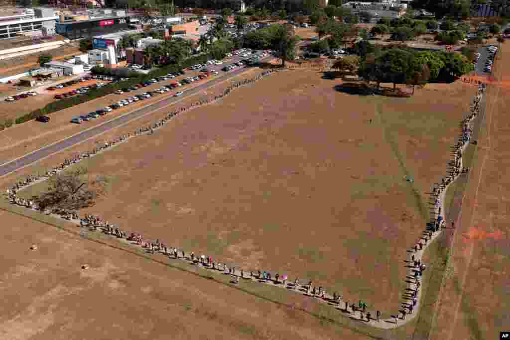 A line of people snakes around a field to enter a COVID-19 vaccination site, as people over age 30 became eligible for a vaccine in Brasilia, Brazil.
