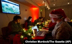 Air Force Col. Amy Glisson and other volunteers answer phone calls from around the world, Dec. 24, 2024, at the NORAD Tracks Santa center at Peterson Space Force Base in Colorado Springs, Colorado.