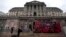 FILE - People hold umbrellas to shelter from the rain as they walk past the Bank of England in London, Aug. 4, 2011.