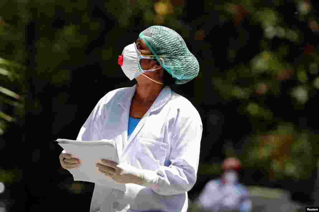 Un médico con una máscara facial habla con un residente durante una verificación puerta a puerta de las personas para averiguar si han desarrollado síntomas de la enfermedad, en el área de Nizaumuddin de Nueva Delhi, India,&nbsp;