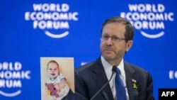 FILE - Israeli President Isaac Herzog shows a photograph of 10-month-old baby Kfir Bibas held by Hamas during a session of the World Economic Forum meeting in Davos on January 18, 2024.