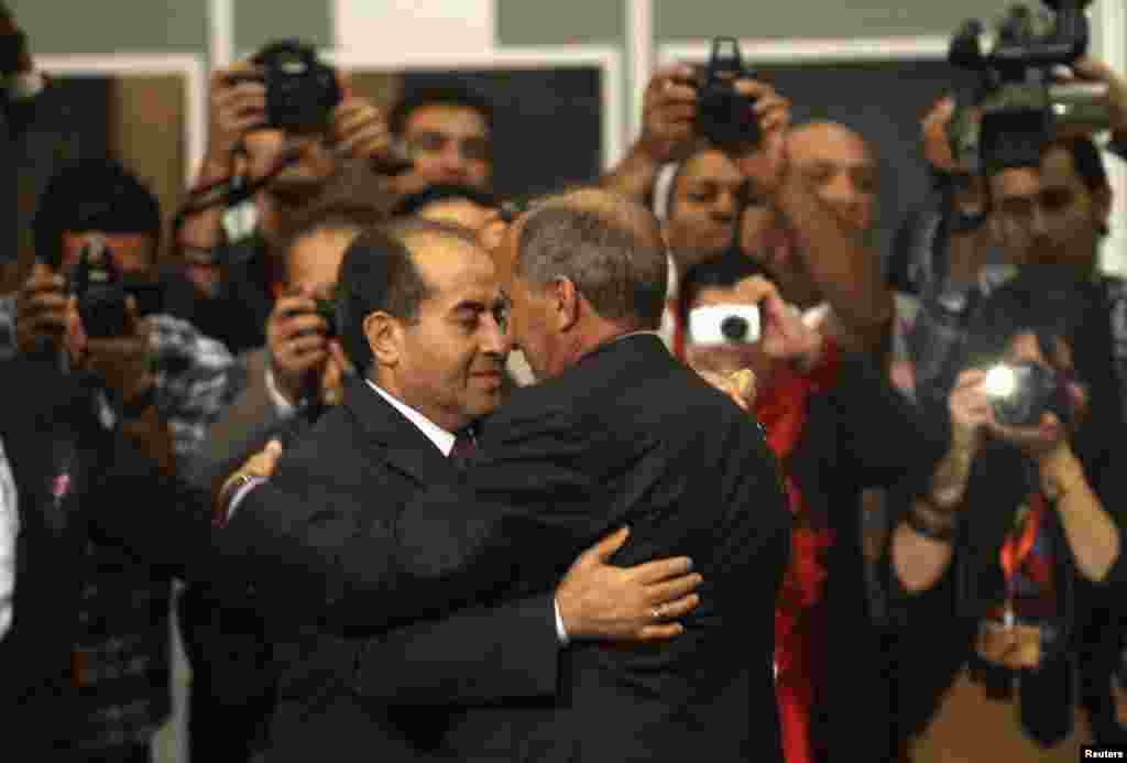Mustafa Abdel Jalil (R), Chairman of the National Transitional Council (NTC) shakes hands with war-time Prime Minister Mahmoud Jibril after handing over power to the national congress in Tripoli August 8, 2012.