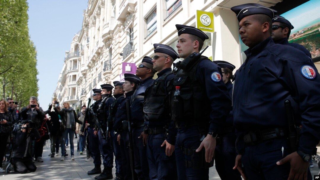 A dozen of police officers stand at attention at the place where a police officer was killed Thursday on the Champs Elysees boulevard, April 21, 2017 in Paris. 