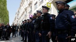 A dozen of police officers stand at attention at the place where a police officer was killed Thursday on the Champs Elysees boulevard, April 21, 2017 in Paris. 