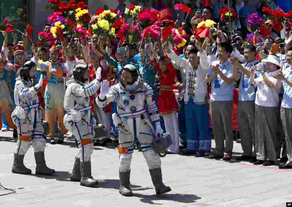 China&#39;s astronauts from left, Wang Yaping, Zhang Xiaoguang and Nie Haisheng wave as they leave the Jiuquan satellite launch center near Jiuquan in western China&#39;s Gansu province. Three astronauts took flight aboard the spacecraft to the dock with China&#39;s Tiangong 1 space lab.