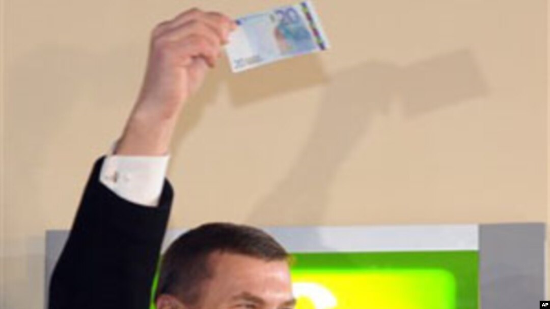 Estonia's Prime Minister Andrus Ansip, lifts a 20 Euro banknote which he withdrew from an ATM cash machine in Tallinn, 01 Jan 2011