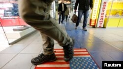 FILE - A man steps on a doormat depicting a U.S. flag, inside a shopping center in Moscow, Russia, Dec. 25, 2014.