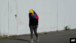 Una mujer, que lleva la bandera de Venezuela, camina después de asistir a una protesta contra los resultados oficiales que declararon al presidente Maduro como ganador de las elecciones presidenciales, en Quito, Ecuador, el sábado 17 de agosto de 2024. (Foto AP/Dolores Ochoa)