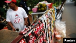 A vendor sells drinks using packets of instant coffee from a stall on a street in central Jakarta, Nov. 27, 2014. 