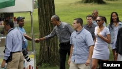 Presiden AS Barack Obama, tengah, berjabat tang an dengan seorang pedagang ketika berjalan-jalan di Central Park dengan anaknya Sasha, kedua dari kanan, dan Malia, kanan, di New York, 18 Juli 2015. 