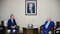 FILE - In this photo released by the Syrian official news agency SANA, the U.N.'s special envoy for Syria Geir Pedersen, left, meets with Syrian Foreign Minister Walid al-Moallem, in Damascus, Syria, Sept. 23, 2019. 