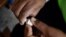 FILE - A member of a vaccination campaign against cholera opens a vial.