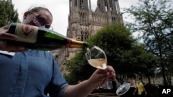 A waitress serves a glass of champagne at La Grande Georgette restaurant in front of the cathedral in Reims, the Champagne region, east of Paris, Tuesday, July 28, 2020. (AP Photo/Francois Mori)